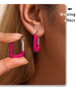 Gros plan d'un modèle portant des boucles d'oreilles en U bicolores rose et argentées