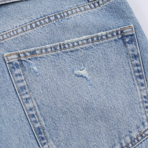 Détail du jean bleu clair montrant la poche arrière avec des finitions déchirées