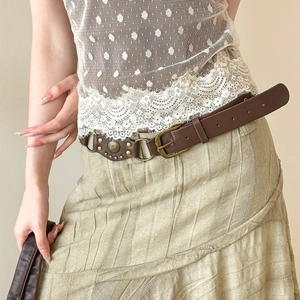 Vintage brown leather belt with bronze rivets styled on a waist over a lace top and skirt