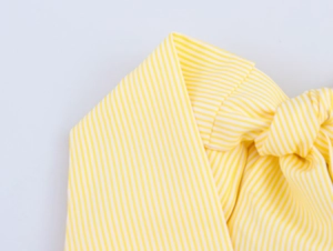 Vue détaillée du tissu à rayures jaunes et blanches avec texture plissée et détail de nœud
