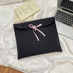 Dettaglio della borsa per laptop nera trapuntata con fiocco decorativo in rosa