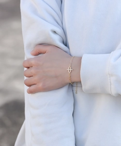 Close-up of a gold chain bracelet featuring a zircon-studded geometric link on wrist