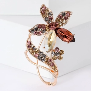 Elegant rose gold flower brooch with sparkling champagne and brown crystals on a white stand