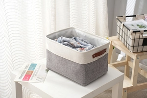 Detail of grey and beige cotton linen storage basket with brown faux leather handles