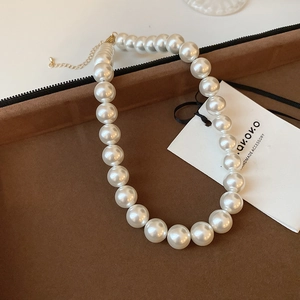 Close-up of pearl necklace with gold clasp in a brown velvet jewelry box display