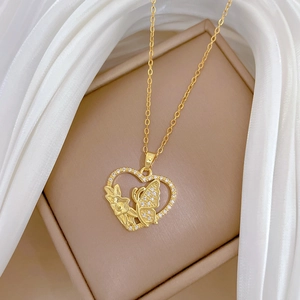 Macro shot of gold heart pendant with butterfly and flower crystal pavé details