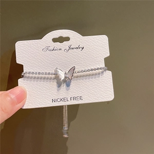 Close-up of sparkling butterfly bracelet with nickel-free jewelry card on green background