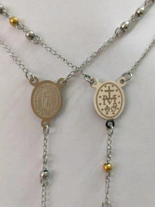 Macro view of stainless steel religious oval medallions and bicolor beaded long chain