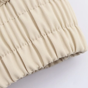Detailed macro view of the beige twill fabric and elastic pleated hem on the trench coat