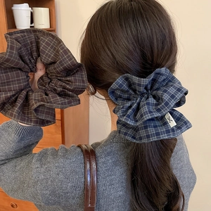 Detail of checkered fabric scrunchie with hand-stitched label for low ponytail styling