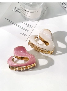 Close-up of heart-shaped hair claws in pink and beige colors with gold metal hardware