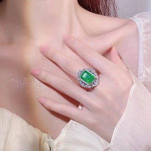 Elegant emerald cut green gemstone cocktail ring with sparkling zircon halo on model's hand