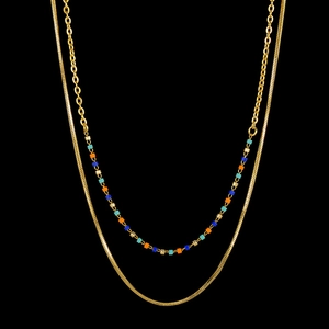 Detail view of double-layer gold necklace with colorful beads on a black background
