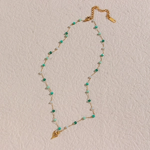 Gros plan sur collier pendentif tulipe doré avec perles vertes et poinçon K18 gravé