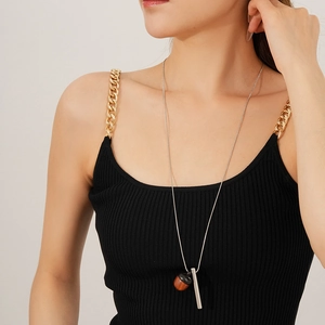 Detail view of a model wearing a wooden acorn pendant necklace with a silver metal bar