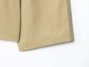 Dettaglio della trama in saia kaki e cuciture fini sull'orlo del trench coat