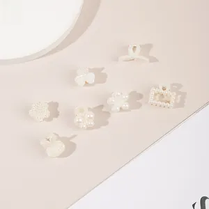 Macro detail of seven mini pearl hair clips in floral and butterfly shapes for women