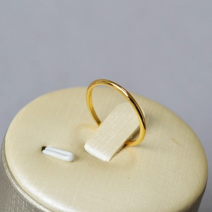 Anello a onda placcato in oro minimalista esposto su un supporto per gioielli
