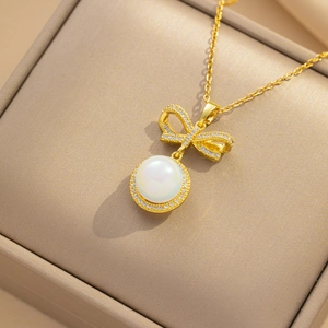 Elegant gold bow necklace with micro-pave crystals and pearl pendant in jewelry box