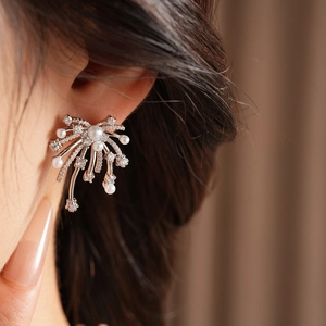 Close-up of sparkling zircon fireworks fan earrings with white pearls on model