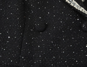 Detailed macro shot of black tweed fabric with sequins and silver embroidered trim