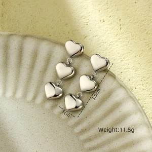 Macro view of triple heart silver earrings on ceramic tray with size and weight info