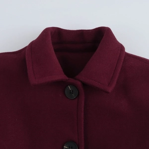 Close-up of deep red wool blend coat collar and black buttons on white background