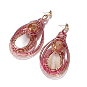 Macro shot of handmade bohemian wire wrapped heart pearl earrings with pink faceted beads