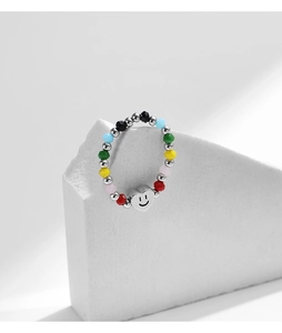 Gros plan d'une bague de perles colorées avec un pendentif smiley en forme de cœur