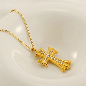 Macro detail of a gold cross pendant with white diamonds inside a white porcelain bowl