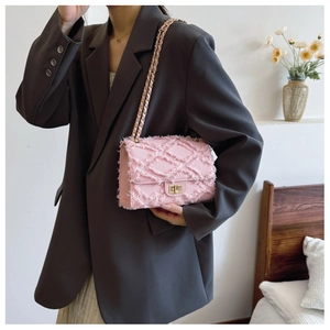 Detail of pink denim crossbody bag showing quilted texture, fringe, and gold twist lock