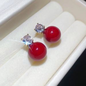 Macro shot of silver needle bow pearl earrings with red pearls and zircon sparkle