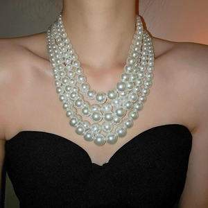 Elegant multi-layer pearl necklace on model with black tube top in soft lighting