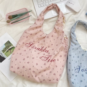 Detail of pink and blue floral canvas tote bags with Szakka Time text on white background