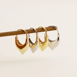 Close-up of gold and silver S925 heart-shaped dangle earrings on a wooden display stand