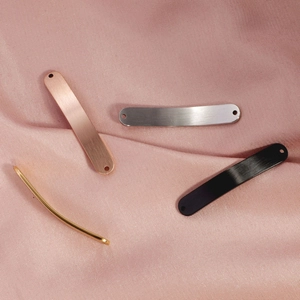 Close-up of brushed titanium steel curved bar pendants in gold, rose gold, silver, and black