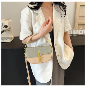 Detail of color-block tote bag with straw texture and golden metal clasp on shoulder strap