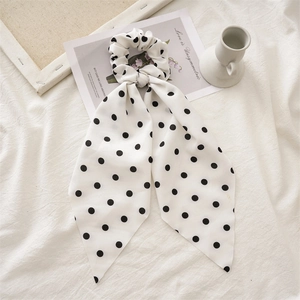 Detailed view of polka dot scrunchie with long ribbons on soft white background fabric