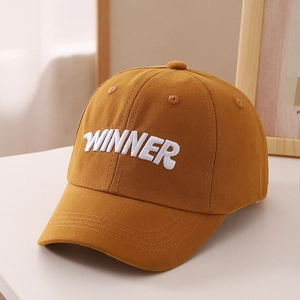 Close-up of ginger yellow cotton baseball cap with white WINNER 3D letter embroidery
