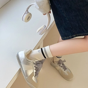Silver and white retro trainers with wide ribbon laces and striped smiley face socks