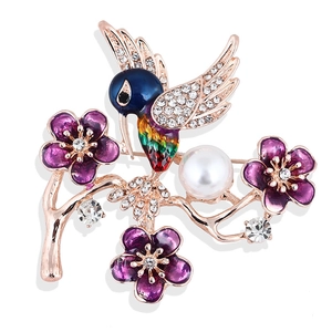 Macro detail of enamel hummingbird brooch with purple flowers and crystal accents