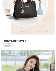 Detail of black pebbled leather handbag with gold star pendant and logo branding