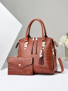 Detail of brown crocodile embossed tote bag and envelope clutch set with cat tassel