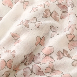 Close-up of white scarf with pink and gray butterfly print and subtle gold glitter details