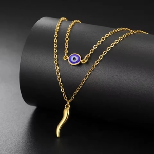 Detail of double-layer gold necklace featuring a blue evil eye and Italian horn pendant