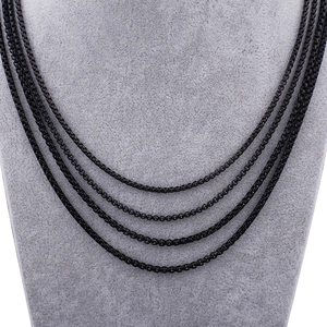 Macro view of four layered black stainless steel box chains on a gray display model