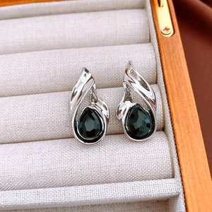 Detailed view of silver teardrop earrings with deep blue gemstone in a gray jewelry box