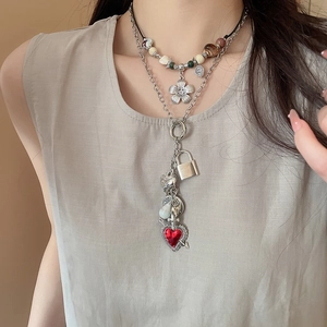 Close-up of layered necklace set featuring a red heart pendant and silver flower charm