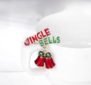 Close-up of Jingle Bells Christmas brooch with red enamel bells and golden lettering