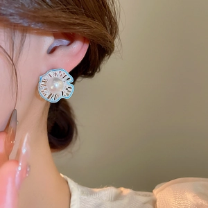 Close-up of model wearing elegant blue floral earrings with center pearl and silver petals